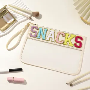 Detail view of a transparent PVC storage pouch featuring colorful SNACKS chenille embroidery