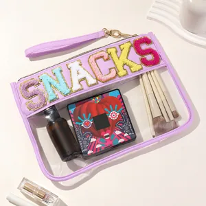 Detail of transparent PVC cosmetic bag with colorful SNACKS chenille patches and brushes.