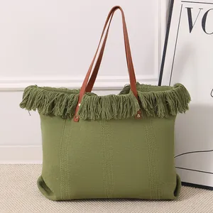 Vista detallada de un gran bolso tote tejido verde con flecos y correas de color marrón