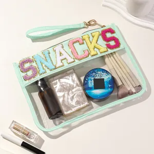 Detail view of mint green PVC transparent pouch with colorful SNACKS embroidery