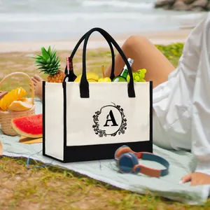 Large canvas tote bag with floral letter A monogram in a sunny beach picnic setting