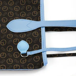 Close-up of printed monogram canvas and light blue leather trim on a tote bag