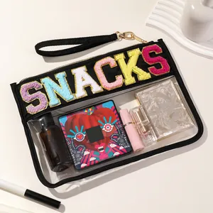 Close-up detail of transparent PVC organizer bag with colorful SNACKS chenille lettering