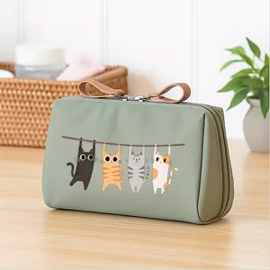 Close-up of the cute hanging cat print on a green waterproof fabric cosmetic bag