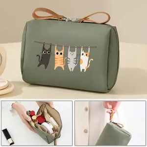 Close-up of green cat print makeup bag showing multi-pocket interior and top handle