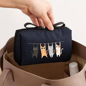 Detail of a navy blue cosmetic bag with cute cartoon cat print being placed in a tote
