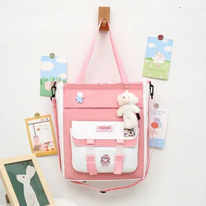 Bolso escolar de lona rosa y blanca con correa ajustable y colgantes decorativos