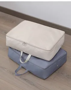 Two stacked compression storage bags for clothes in beige and blue-grey tones.