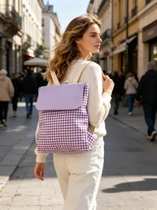 Detail view of a purple gingham cotton drawstring backpack worn on an urban street