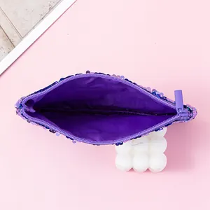 Detail of the purple reversible mermaid sequin pouch interior on a pink backdrop