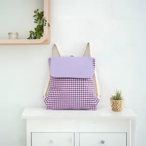 Detailed lifestyle shot of a purple gingham drawstring cotton backpack on a white cabinet