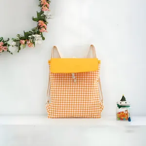 A fresh yellow and white checkered drawstring cotton backpack on a clean white desk