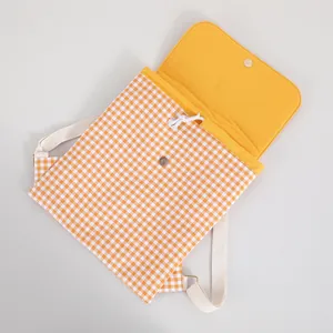 Detail view of orange gingham drawstring backpack with yellow lining and magnetic snap.