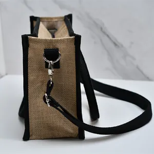 Dettaglio laterale della borsa tote in juta con tracolla nera rimovibile e moschettone