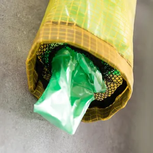 Detailansicht eines wandmontierten gelben Netz-Organizers für Plastikmüllbeutel.