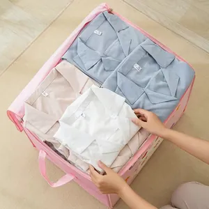 Detailed view of a pink cartoon pattern storage bag being filled with folded clothes