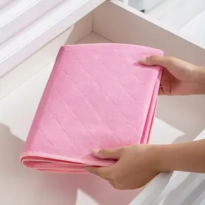 Close-up of a pink quilted non-woven fabric storage bag being placed into a white drawer
