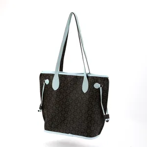 Close-up of a brown printed tote bag featuring light blue contrast handles and trim