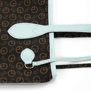 Macro detail of a brown printed tote bag with light blue contrast leather straps.