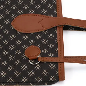 Close-up of a fashionable printed tote bag featuring brown leather straps and stitching.