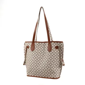 Side view of large printed tote bag featuring brown faux leather trim and dual handles.