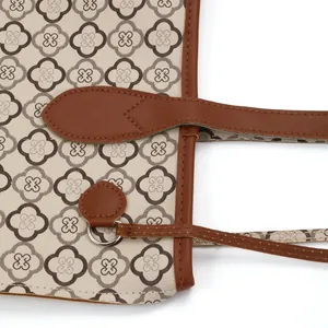 Close-up of retro printed tote bag with brown leather straps and detail stitching.