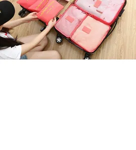 Detail view of woman organizing pink travel storage bags with clothes in a suitcase