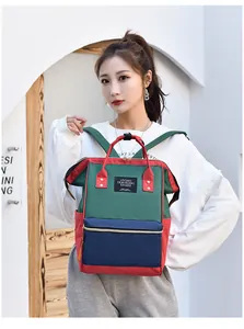 Asian woman wearing a multi-functional color-block mommy backpack in green and red