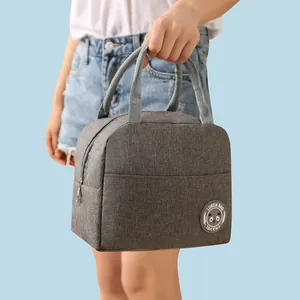 Detail view of a grey insulated lunch bag with panda logo being held by a handle.