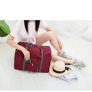 Macro view of a maroon foldable travel bag being used by a model in a travel scene.