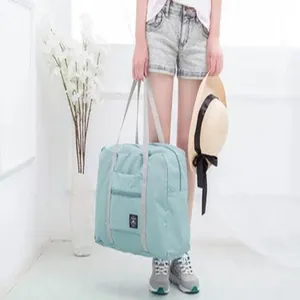 Detailed lifestyle view of a model carrying a mint green foldable waterproof travel bag