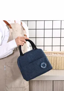 Isolierte blaue Lunchtasche, gehalten von einer Person mit Schürze in der Küche
