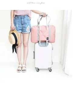 Large pink foldable travel bag attached to a white suitcase handle for easy transport.