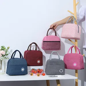 Insulated portable lunch bags in various colors displayed on a table and wooden rack