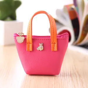 Gros plan sur un mini porte-monnaie rose avec poignées orange et badge ours doré