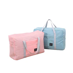 Two large foldable travel storage bags in pink and blue with front zipper pocket.