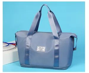 Close-up detail of a blue expandable travel bag with stylish logo and hand straps.