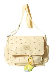 Cute cream canvas shoulder bag with pink floral pattern and decorative flower charm