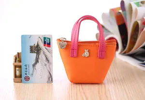 Mini porte-monnaie en cuir couleur bonbon à côté d'une carte de crédit pour l'échelle.
