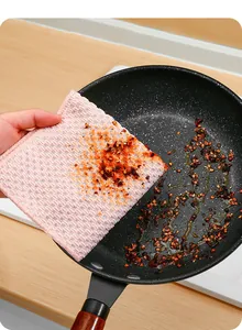 Close-up of pink corn kernel texture cleaning cloth wiping grease off a black frying pan