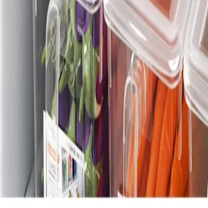 Close-up detail of clear food-grade refrigerator storage bin with fresh vegetables inside