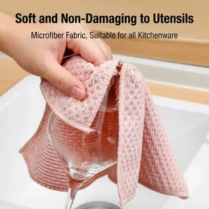 Pink microfiber kitchen cloth with corn kernel texture wiping a clear wine glass.