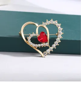 Macro view of golden heart-shaped brooch with a red crystal and white rhinestones