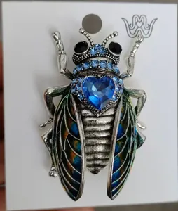 Dettaglio di una spilla a insetto vintage con un grande strass a cuore blu intenso