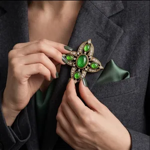 Vintage hollow cross brooch with green stones pinned on a professional grey suit jacket