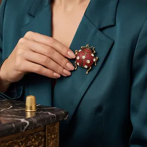 Vintage ladybug beetle brooch with red rhinestones worn on a teal blazer's lapel.