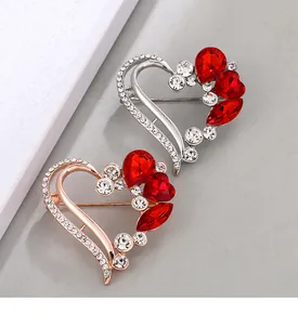 Close-up of elegant heart-shaped brooches with red crystals and silver or rose gold plating.