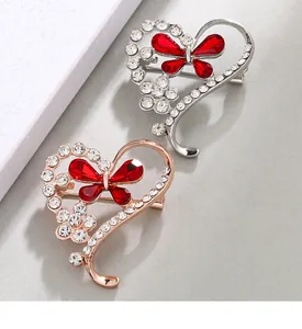 Detailed view of silver and rose gold heart brooches with red crystal butterflies