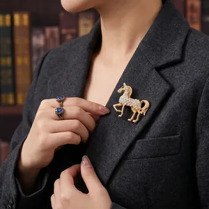 Elegante goudkleurige paardenbroche met witte steentjes op een donkergrijze blazer