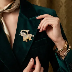 Elegant gold alloy elephant brooch with rhinestones on a green velvet blazer lapel.